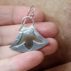 Lotus earrings in bronze and argentium silver designed and made by Mocahete. Displayed in hand.
