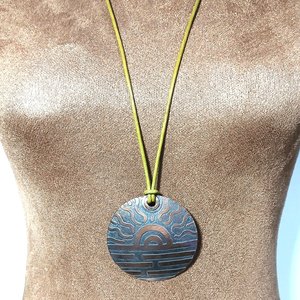 Adjustable length etched copper pendant on leather cord displayed on mannequin.