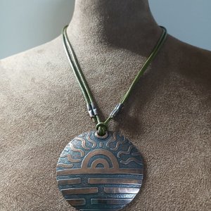 Showing adjusted length of copper pendant hung on leather cord. Displayed on mannequin.