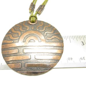 Etched large copper pendant displayed against ruler to show size.