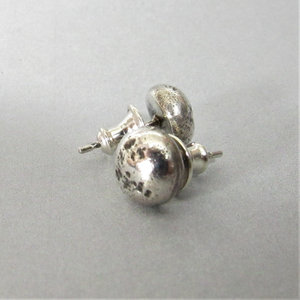 A rustic pair of silver stud earrings with a textured finish. The earrings are round and have a post back.