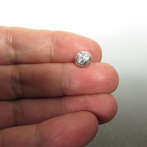 Small, silver, round sterling silver nugget stud earrings with a textured surface. Photo in hand.