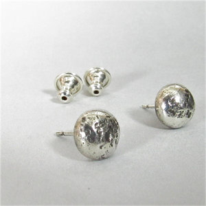 A pair of silver stud earrings with textured round tops. The earrings have a post and ss clutches.