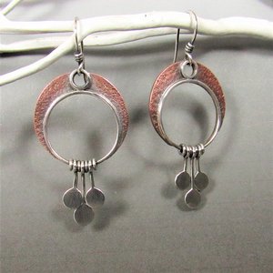 Crescent moon earrings made in copper and sterling silver with 3 silver paddles hanging beneath. Lovely movement, lightweight. 2" tall and 1" wideDisplayed on white twig against grey background.