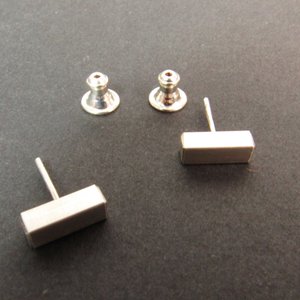 A pair of sterling silver rectangular stud earrings with posts. The posts are attached to silver backings.