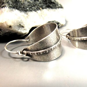 Classic basket style argentium silver hoops with a decorative strip of beaded wire against a sand textured back ground. Oxidized and polished, finished with securely wrapped sterling ear wires. Background is black and white rock on grey paper 1.25 inch tall,  7/8 inch wide.