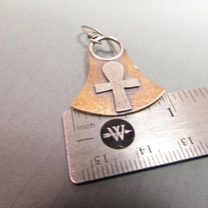 Mixed metal, bronze and silver ankh earrings. Body of earring shaped similar to the egyptian lotus motif with ankh on the front, suspended by silver ring and ear wires. 1.5" tall and 1" wide at widest point.  Displayed against ruler to show width.  On grey background.
