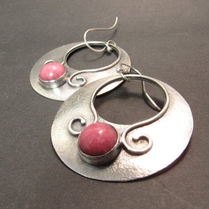 Lovely, large argentium sterling silver earrings in a gypsy style hoop dangle with earthy pink rhodonite cabochons. Swirling ss wire embellishments. Hoops are 1.75" tall x 1.5 inch wide. Statement earrings, oxidized for depth and drama.