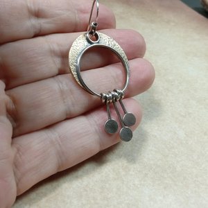 Photo in hand of artisan crescent moon earrings in bronze and silver