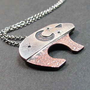 Handcrafted Ursa bear necklace in sterling silver and copper, with celestial moon and star cutouts, smooth flowing sterling silver bail, and sturdy 18 inch sterling chain with handmade findings. Bear measures 3/4 tall x 1.25" wide. Sterling silver chain and handmade findings complete the necklace. Displayed on grey background.