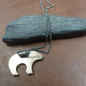 Reverse side of bear pendant by Mocahete showing makers mark. Rock and leather background.