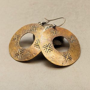 Handmade mixed metal coin earrings propped on rock and neutral background.