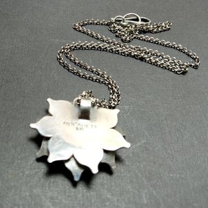 Reverse side of argentium lotus flower pendant showing makers mark and purity stamp.