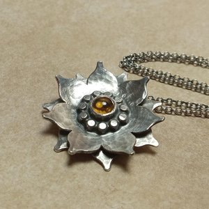 Lotus flower pendant with citrine, hammer textured argentium SS. Photo on sand color paper.