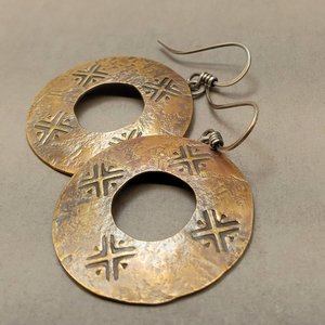 Close-up showing sand-textured bronze surface and stamped edge detail on mixed metal coin style earrings by Mocahete