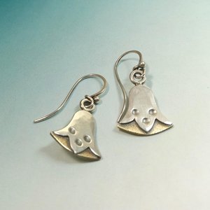 Bronze and silver egyptian lotus earrings by Mocahete on blue background.