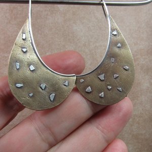 Unusual bronze and SS earrings photographed against hand.