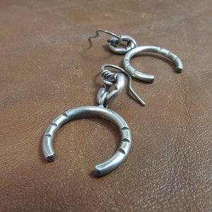 Bold and simple contemporary sterling silver earrings crafted from Argentium have lovely swingy movement. The double open hoop design allows for them to articulate. Lightweight, comfortable, 5 grams per earring. 1.75” long and 7/8” at widest point. Displayed on brown leather.