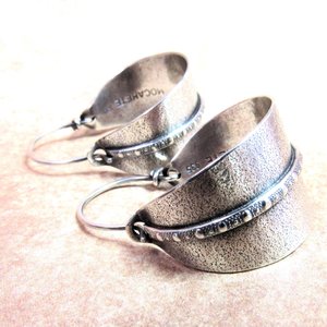 Sterling silver hoop earrings basket style fancied up with a strip of patterned  silver wire against textured argentium silver. A perfect sterling silver hoop earring for every occasion!  Oxidized, polished, finished with sterling ear wires. 1.25" or 3.1cm tall,  7/8" or 2.22cm wide. Displayed on neutral background.