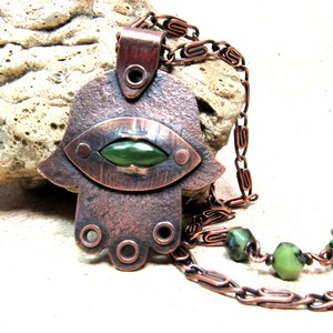 Handcrafted copper, jade and chrysoprase hamsa pendant necklace. 2" tall x 1.5" wide, 24.5" copper scroll chain with 3 faceted chrysoprase beads on each side. All riveted design. Displayed against rock on neutral background.