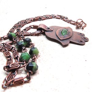 Handcrafted copper, jade and chrysoprase hamsa pendant necklace. 2" tall x 1.5" wide. This photo highlights the 24.5" copper scroll chain with 3 chrysoprase beads on each side.. All riveted design. Displayed on neutral background.