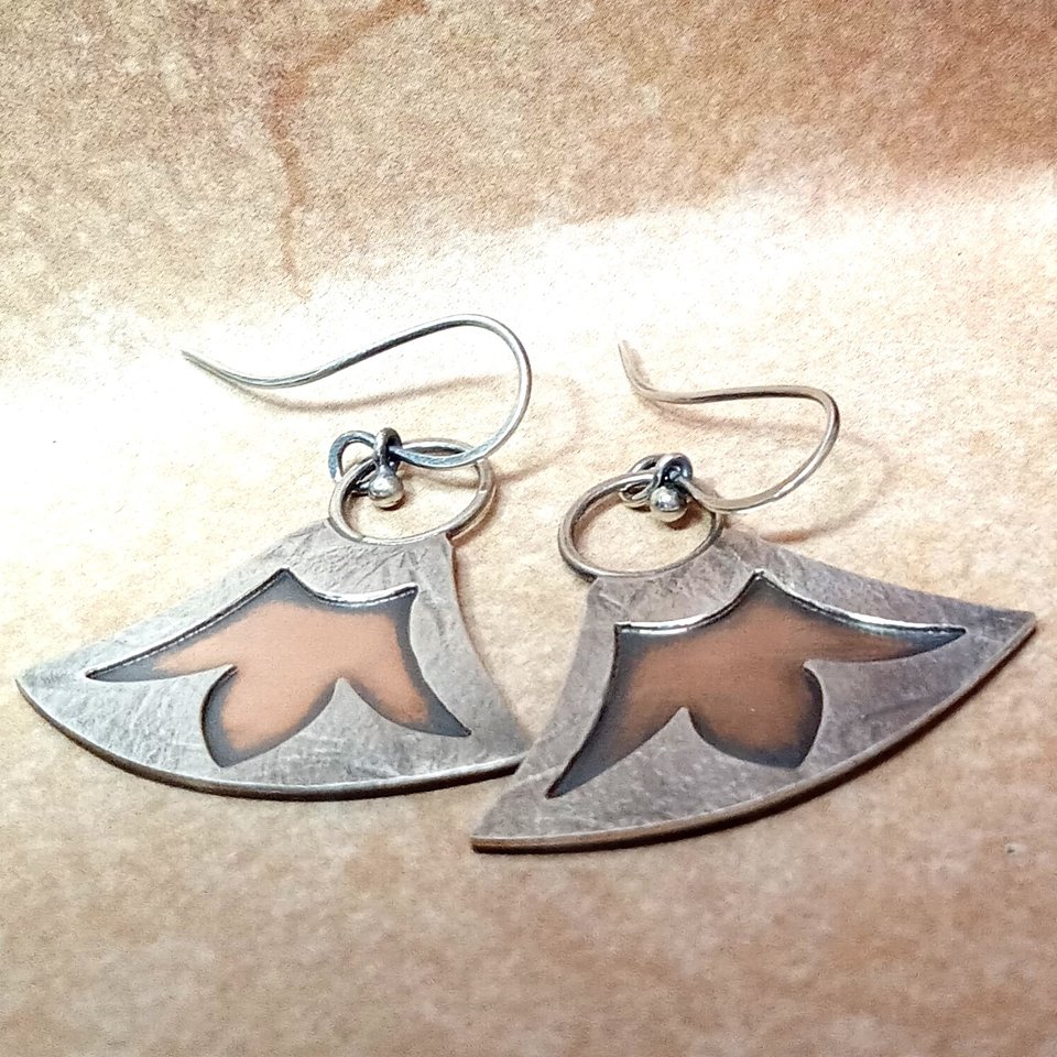 Mixed metal, bronze and argentium silver earrings with lotus design. Displayed flat on neutral background.