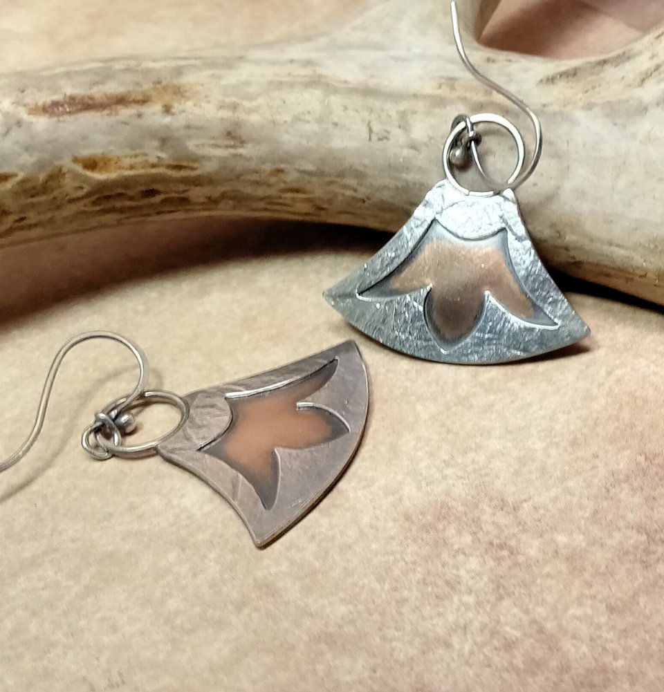 Bronze and argentium silver mixed metal lotus earrings by Mocahete displayed against antler on neutral background.