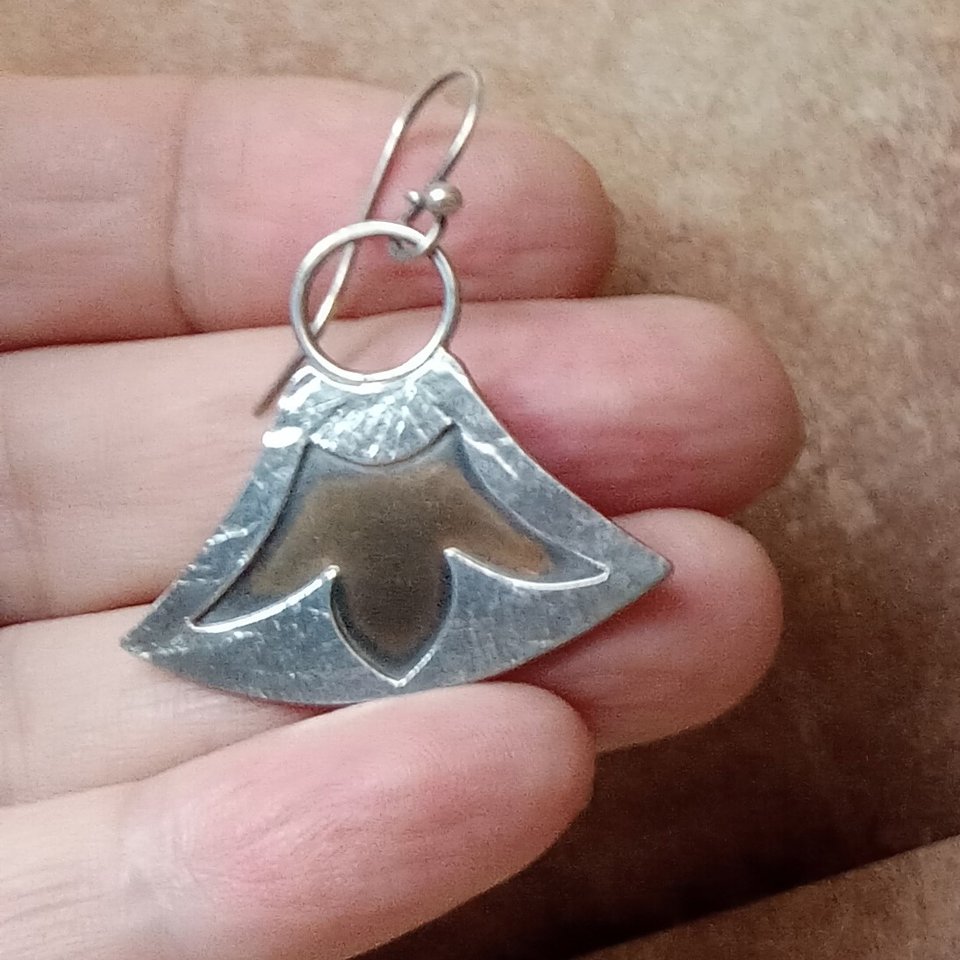 Lotus earrings in bronze and argentium silver designed and made by Mocahete. Displayed in hand.
