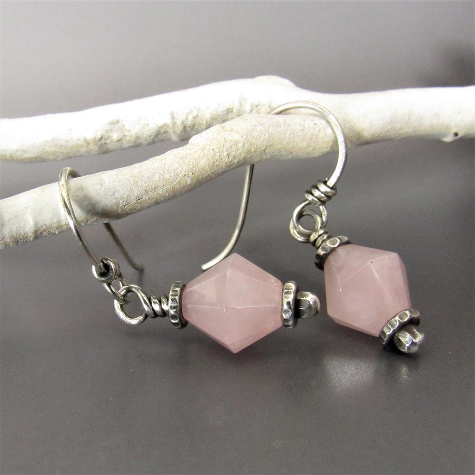 Pink quartz dangle earrings displayed against a gray background with white branch.