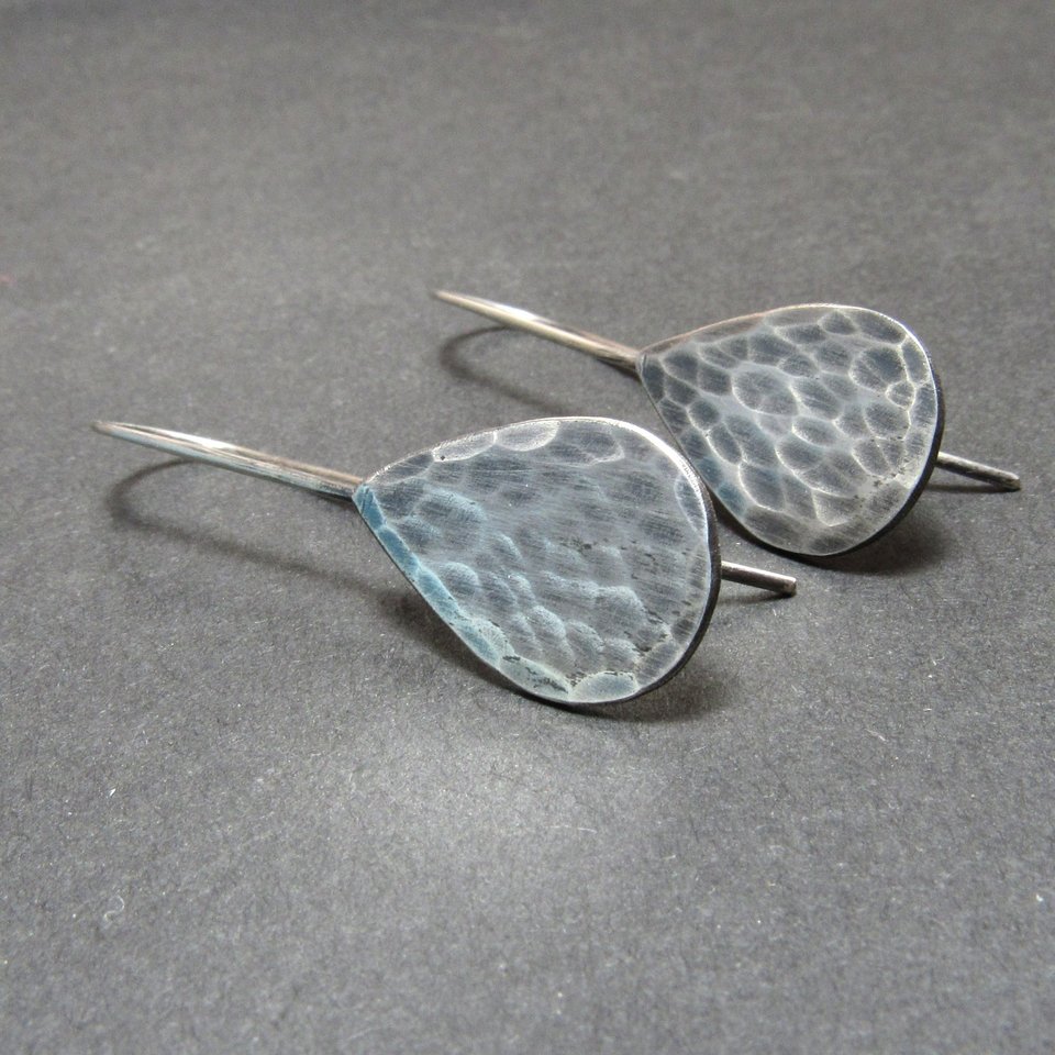 Sideview of hammered sterling silver teardrop earrings, displayed on grey background.