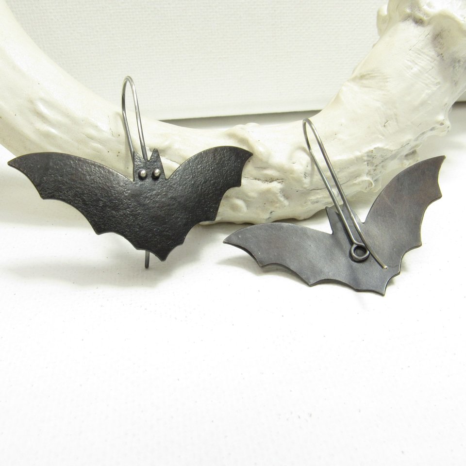 Bat earrings showing reverse side of one.  Displayed on white antler and background.