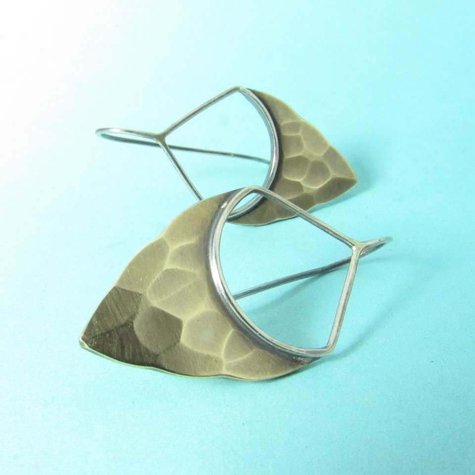 Striking, handcrafted sterling silver and bronze earrings have a two tone geometric design. Hammered for a knapped arrowhead appearance , oxidized and polished. Sterling silver fixed ear wire, 1-5/8" tall and 7/8" wide.  Displayed against blue background.