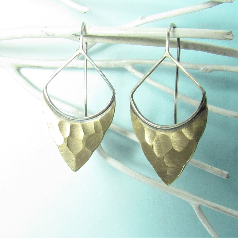 Striking, handcrafted sterling silver and bronze earrings have a two tone geometric design. Hammered for a knapped arrowhead appearance , oxidized and polished. Designed with a sterling silver fixed ear wire which holds them close to flatter your face. 1-5/8" (4.12cm) tall and 7/8" (2.2cm) wide.  Displayed against blue background on white branch.