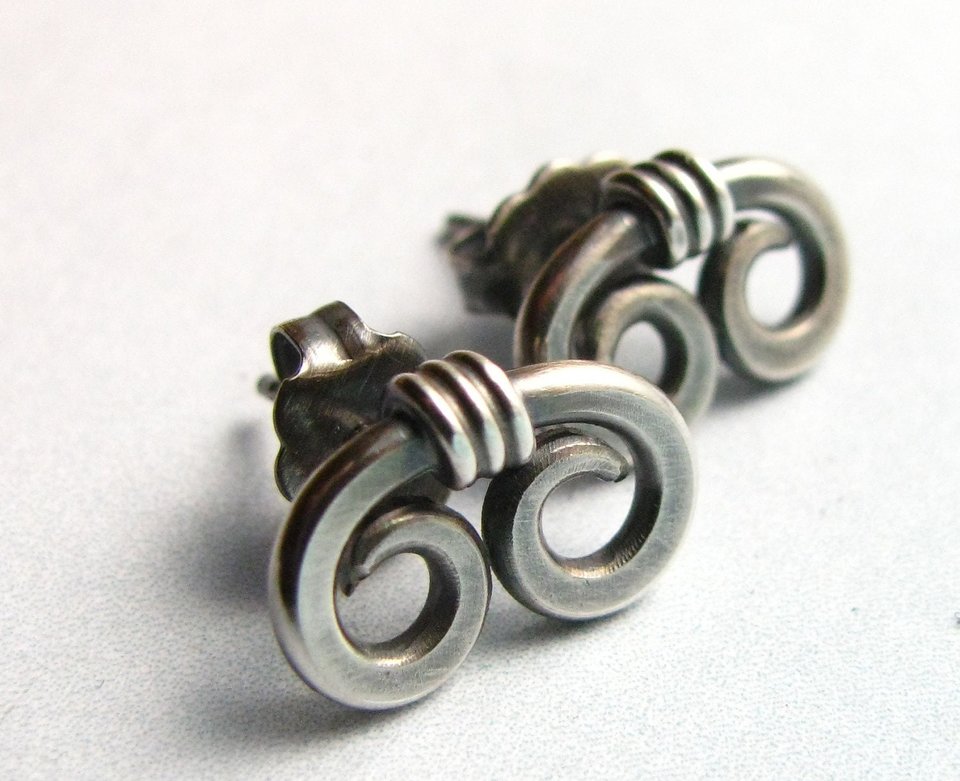 A pair of silver earrings with a unique, twisted design. Each earring features two connected loops, creating a swirling, organic spiral shape.
