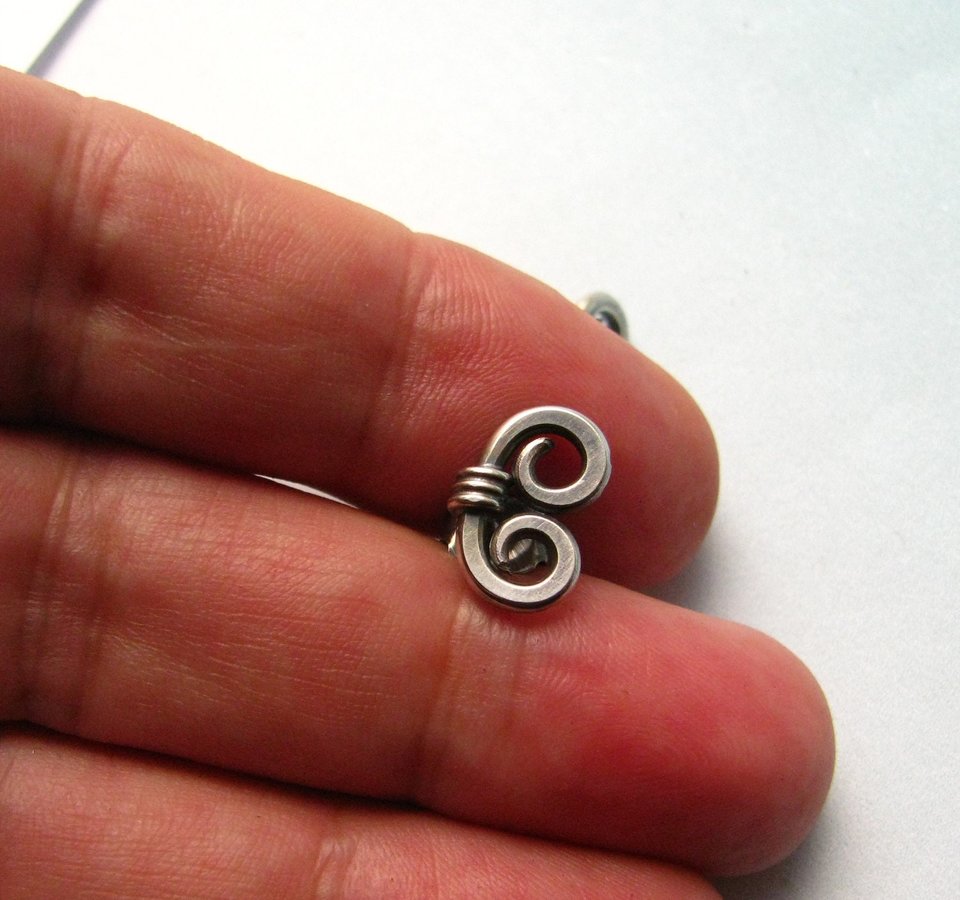 Sterling silver spiral stud earrings photographed in hand.