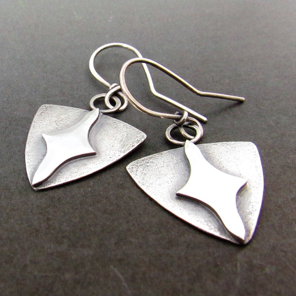 Shield shaped earrings with a star design in the center. Crafted from argentium sterling silver. Inspired by designs from the middle ages. Dangle style, lightweight and comfortable at 3 grams each, they measure 1.5 inch tall and .75 inch wide.