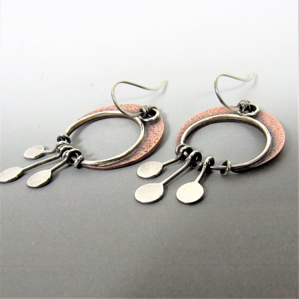 Copper crescent moon earrings with three argentium sterling silver paddles hanging beneath. Lightweight and easy to wear. apx. 2" long and 1" wide. Displayed on grey background.