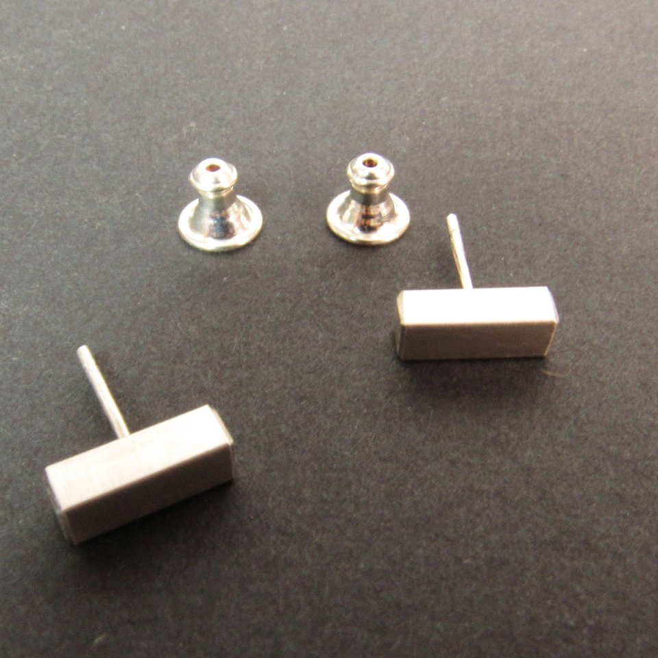 A pair of sterling silver rectangular stud earrings with posts. The posts are attached to silver backings.