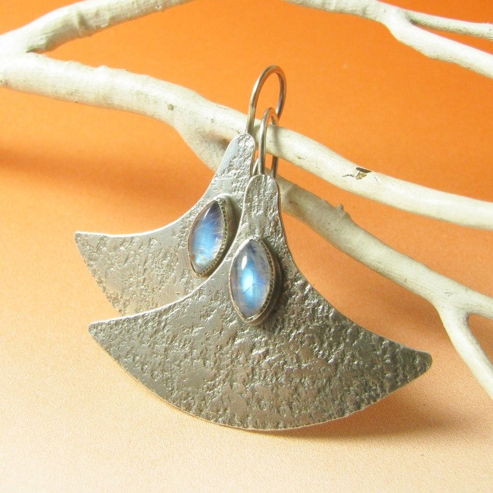 Large, futuristic argentium sterling silver and rainbow moonstone earrings with a touch of rusticity. Unusual and unique earrings that are modern with hints of the past. 1.5 inches tall x 1.75 inches wide. Displayed against orange background and white twig.