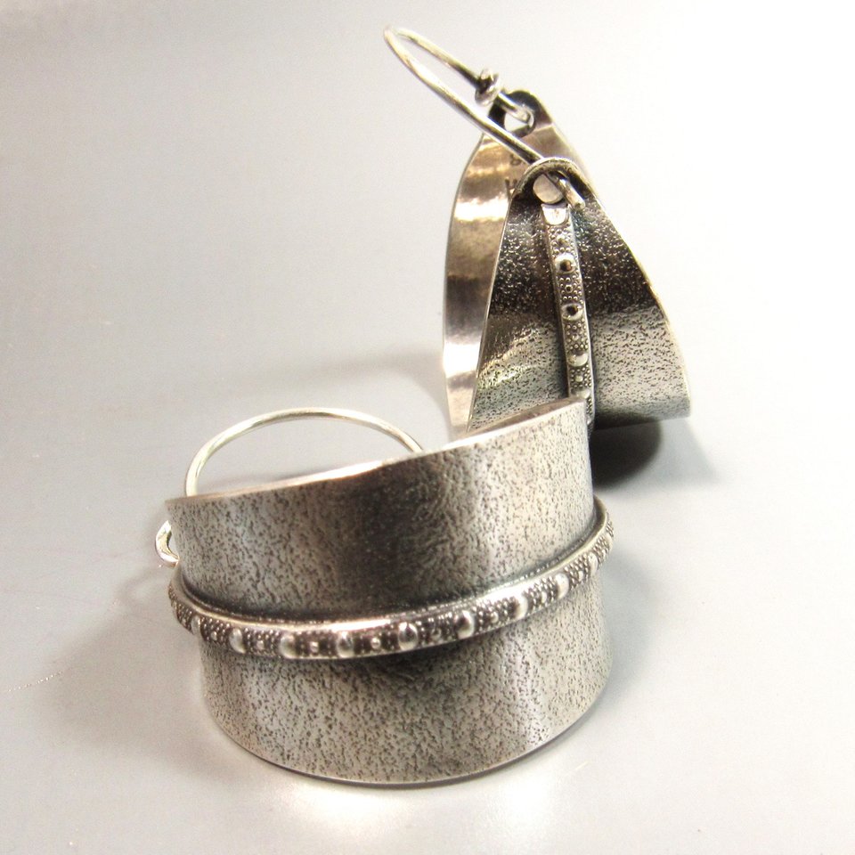 Sterling silver hoop earrings basket style fancied up with a strip of patterned  silver wire against textured argentium silver. A perfect sterling silver hoop earring for every occasion!  Oxidized, polished, finished with sterling ear wires. 1.25" or 3.1cm tall,  7/8" or 2.22cm wide. Displayed on neutral background.