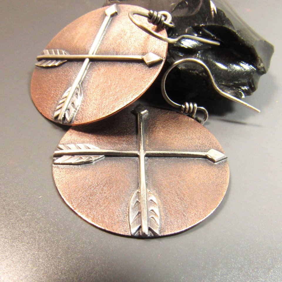 Large mixed metal disc shaped crossed arrow earrings in copper and sterling silver. !.75 inch tall x 1.25 inch wide, lightweight at only 5 grams per earring