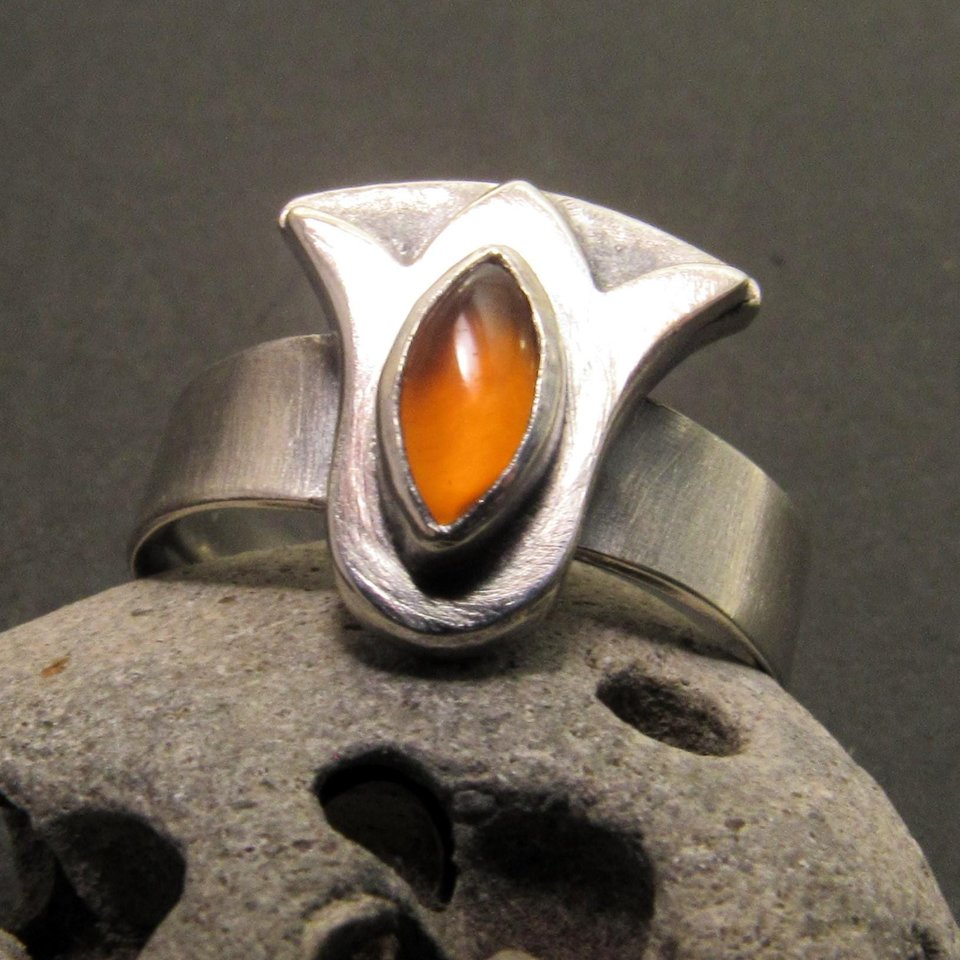 Carnelian lotus ring crafted from superior argentium sterling silver and a marquis cut carnelian cabochon. This particular lotus design is inspired by the ancient Egyptian lotus motif while the carnelian being associated with the Sun God Ra or Re further informs the Egyptian connection..Simple but powerful design with a nice weighty heft. The band is a comfort fit style and measures a 5mm wide. The lotus is apx. 14mm x 14mm. Size 8 and can be sized up to 8.5 if needed. Oxidized and polished.