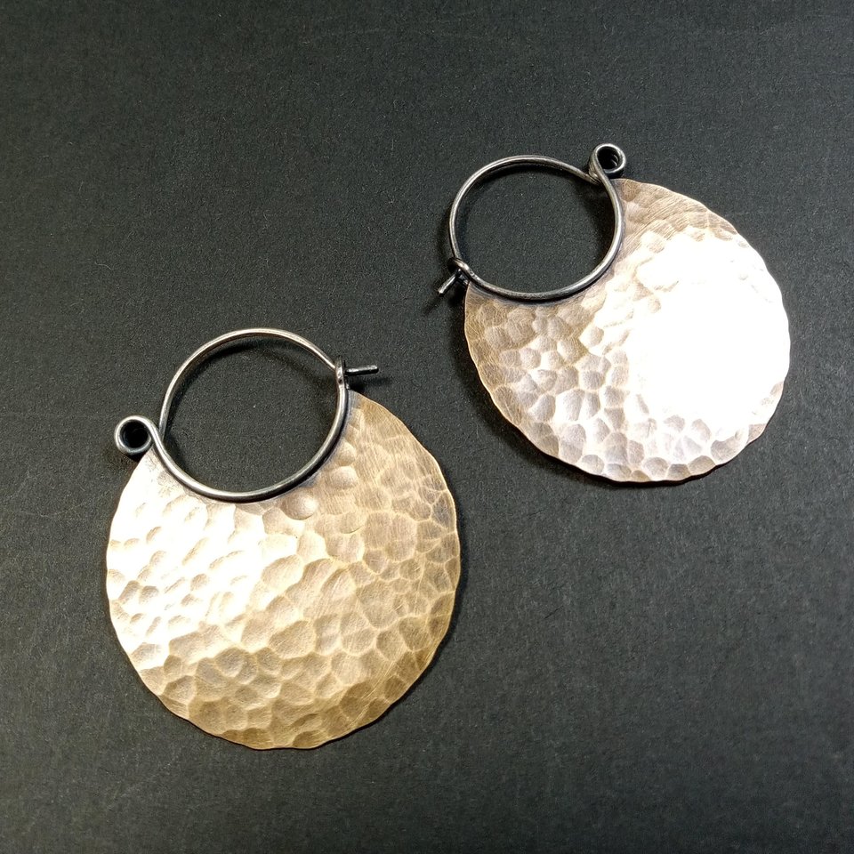 Large hammered bronze hoops with argentium spring closure on dark background.