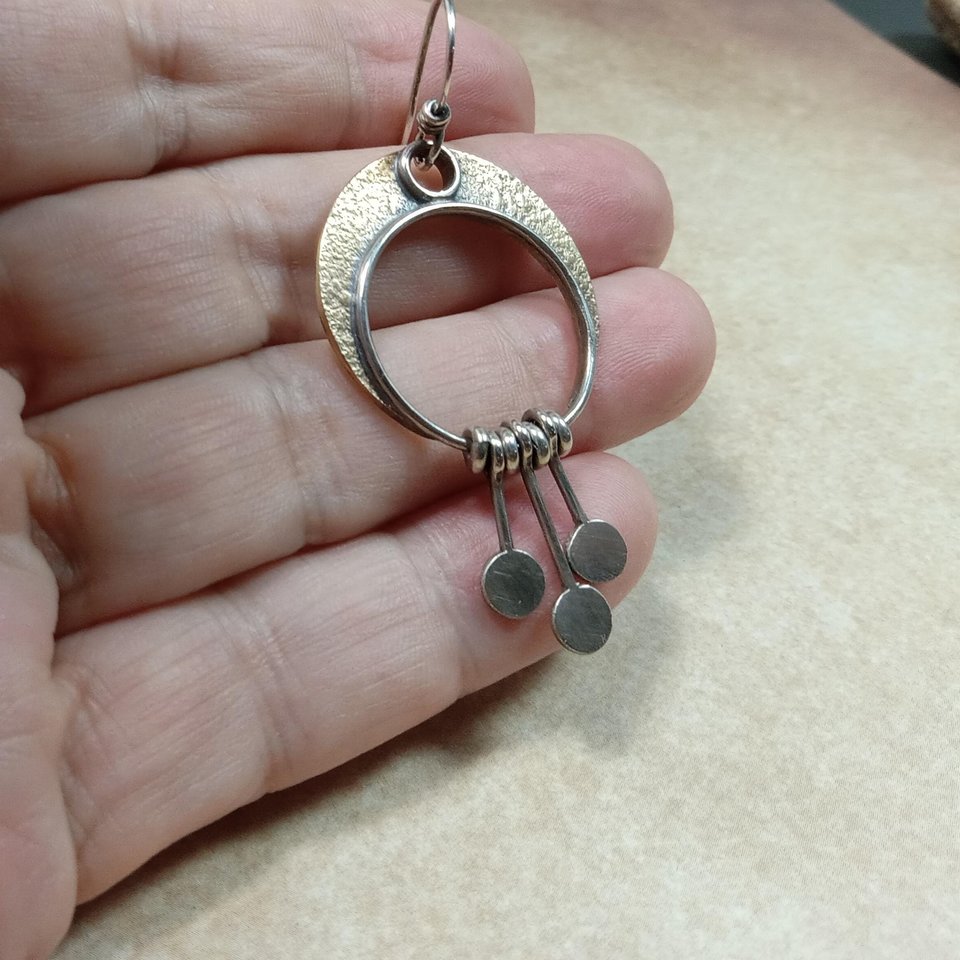 Photo in hand of artisan crescent moon earrings in bronze and silver