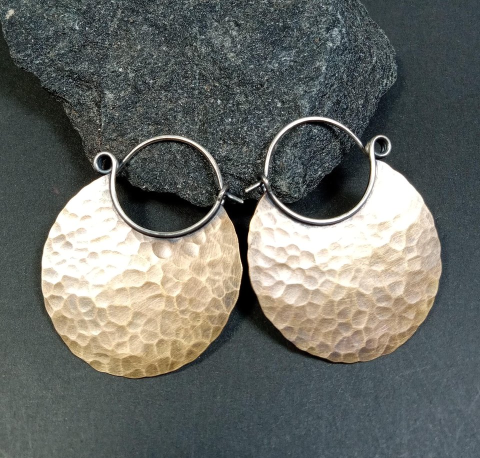 Large hammered bronze hoop earrings with oxidized finish on black background.