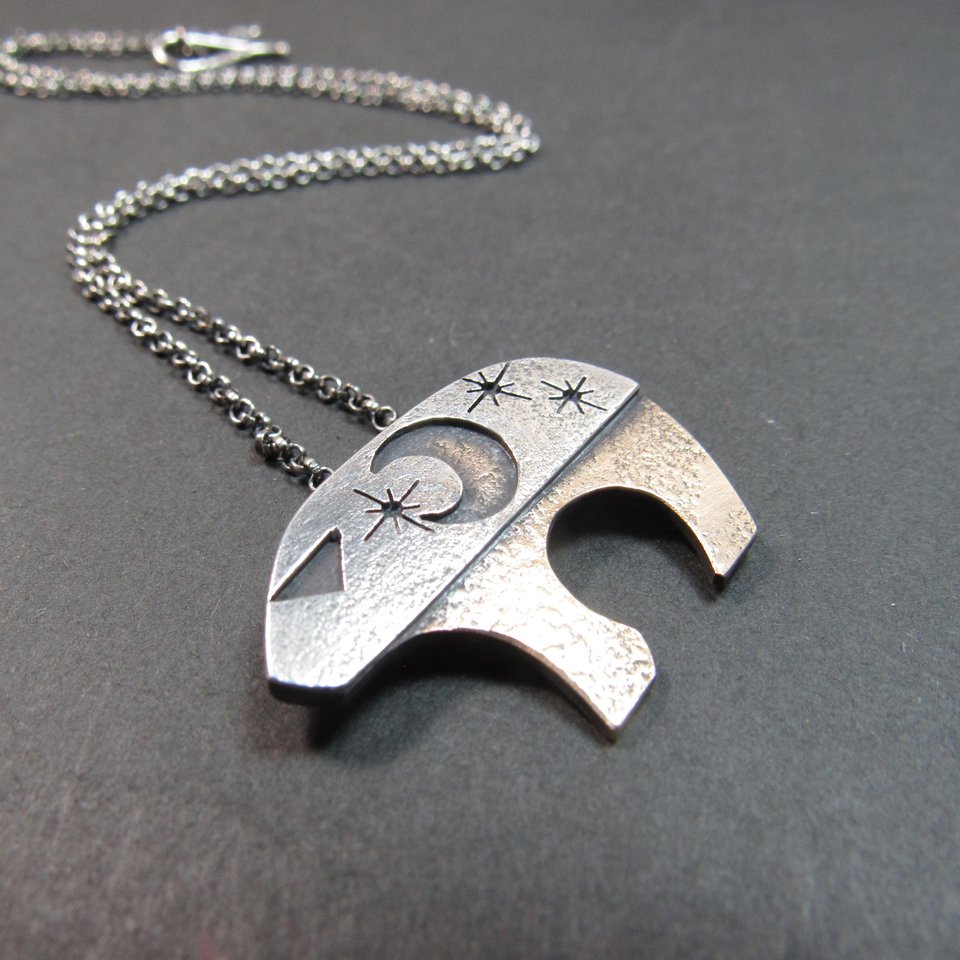 Mixed metal bear pendant necklace by Mocahete on dark background.