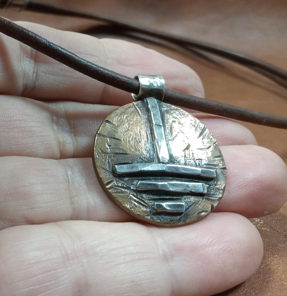 Close up of grounding symbol pendant for men or women, adjustable leather cord, photo in hand.