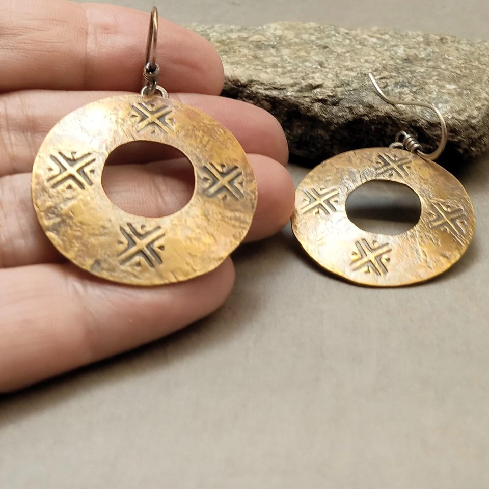 Mixed metal coin style earrings displayed in hand to show scale and organic artisan texture
