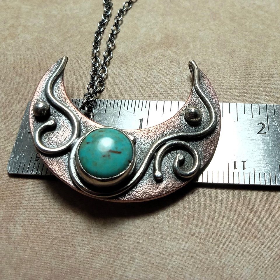 Mixed metal turquoise moon pendant against ruler to show size.