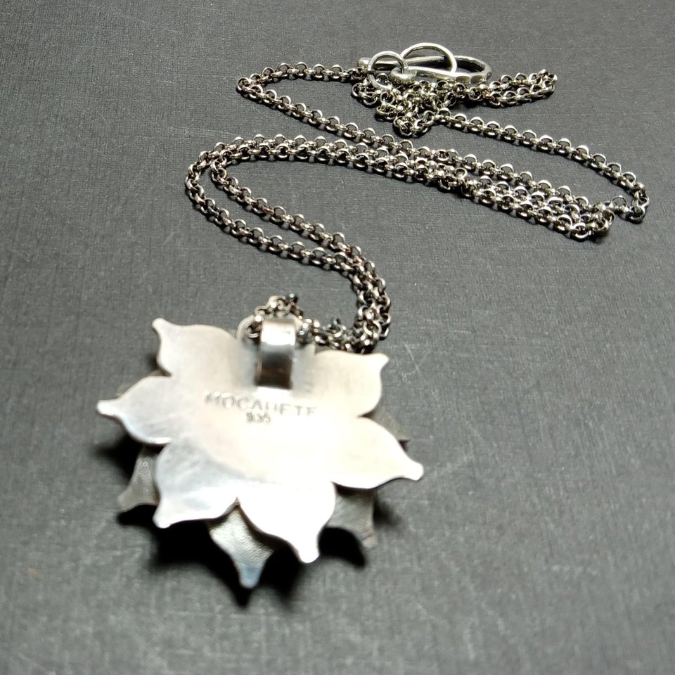 Reverse side of argentium lotus flower pendant showing makers mark and purity stamp.